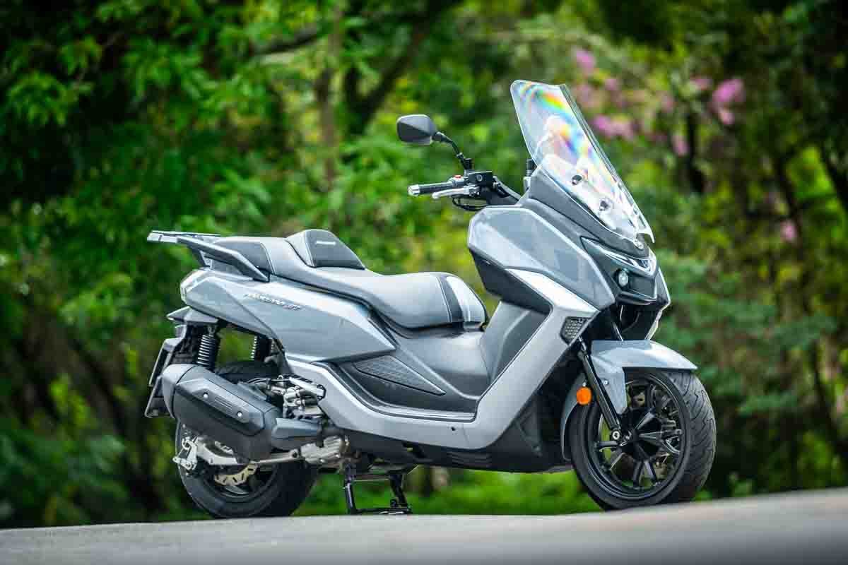 Maxsym 400 GT cinza parada em área arborizada, maxiscooter mais cara de revisar no plano de preço fixo