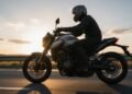 Motociclista de capacete com intercomunicador na lateral em estrada, ilustrando se usar intercomunicador dá multa