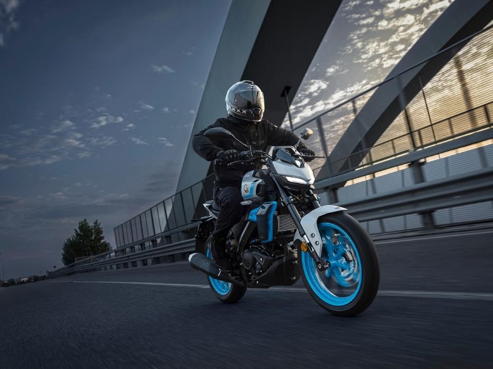 Piloto roda com a naked Yamaha MT-125 2027 azul e branca em uma ponte